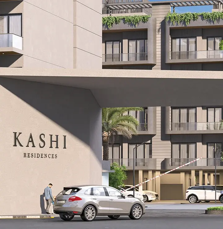 Entrance gate of ganga realty Kashi Residences with a silver car passing through the security barrier and modern residential building